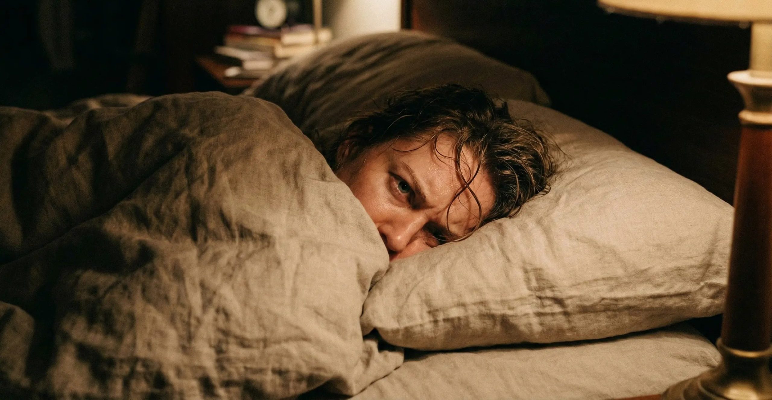 A person lying in bed unable to fall back asleep after waking up at night